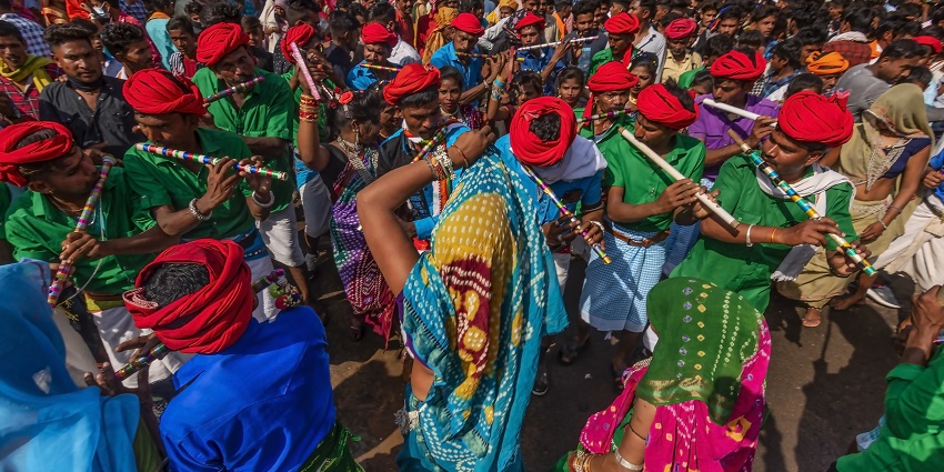 An image of the Bhagoria festival where people are dressed in traditional attire, dancing and playing musical instruments.