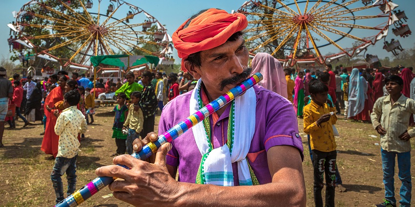 An image showing a Bhil tribe man playing the flute during a unique tribal festival in India.