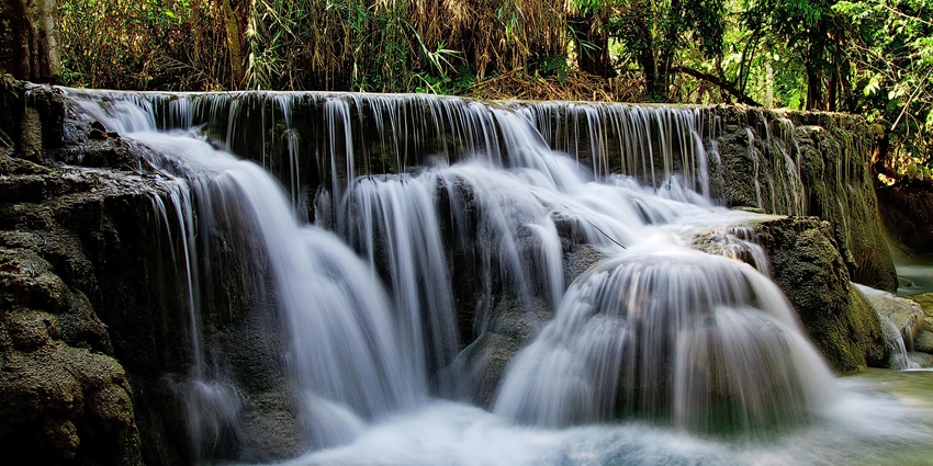 Waterfall in Mussoorie flowing on a rocky surface surrounded by greenery