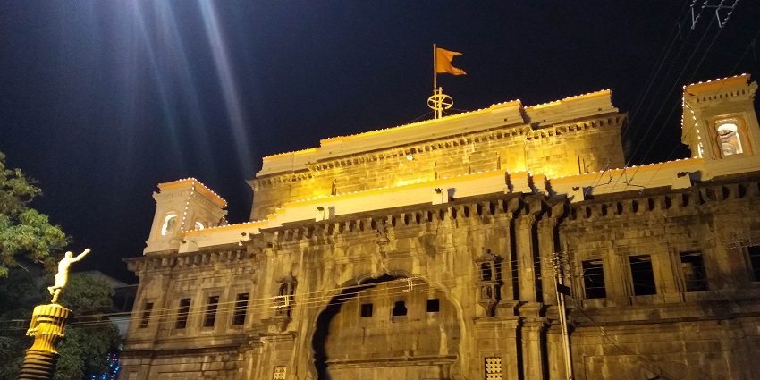 Illuminated Bhavani Mandap, one of the best Kolhapur Temples, at night, with a flag atop