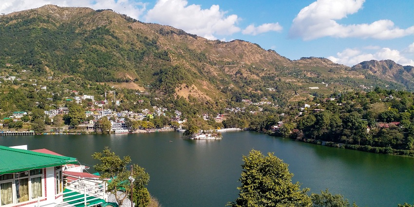 Bhimtal lake with a water body reflecting the green hills and buildings on the hills
