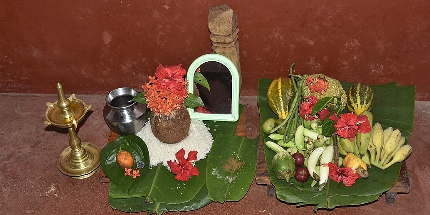 An image of a traditional Indian offering with a lit oil lamp, decorated coconut, during the Bisu Parba