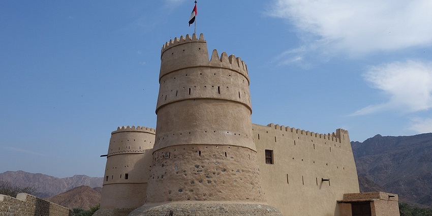 A scenic view of Bithnah Fort, showcasing its historic architecture against a mountainous backdrop.