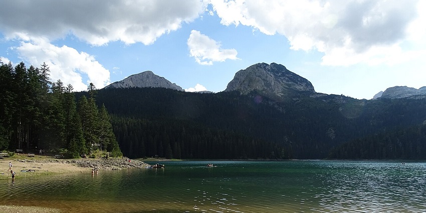 Famous Black Lake of Montenegro under a clear sky, surrounded by mountains and greenery