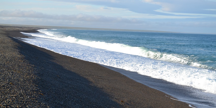 Stunning black sand beach in Prince William Sound, Alaska, surrounded by rugged coastal beauty.