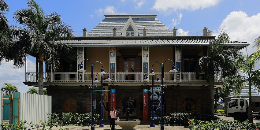 An image of the Blue Penny Museum with dormer windows, palm trees, and a wrap-around balcony is the best place near Rose Hill Mauritius.