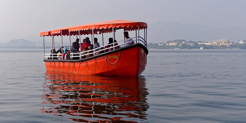 The tourists enjoying their boat ride at Lake Pichola and the beautiful hotel in the background