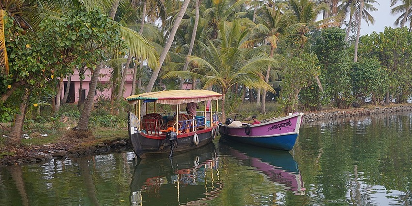 Tourists enjoying a peaceful boat ride on one of the Lakes in Kerala with lush greenery around.