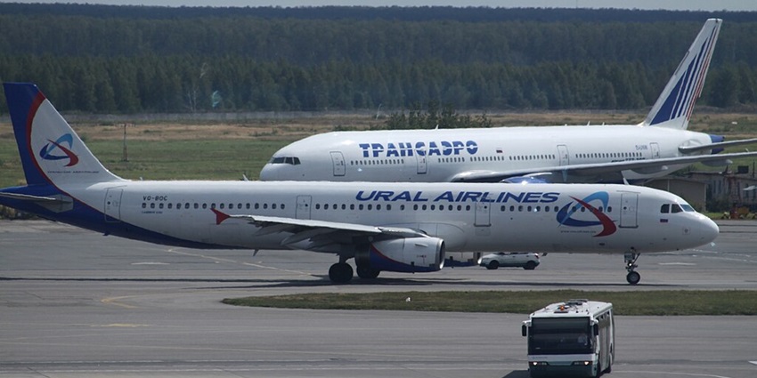 Two aircraft are parked on the runway while a bus moves in front, showcasing airport ground operations