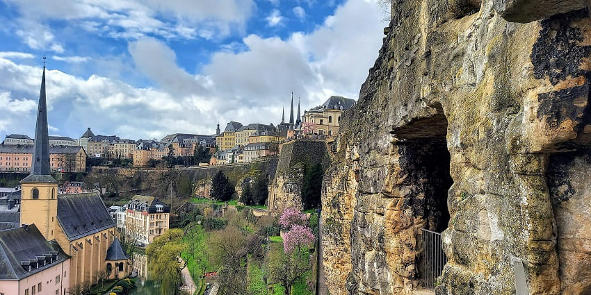 The Historic cityscape shows old buildings with ancient stone walls and lush greenery.