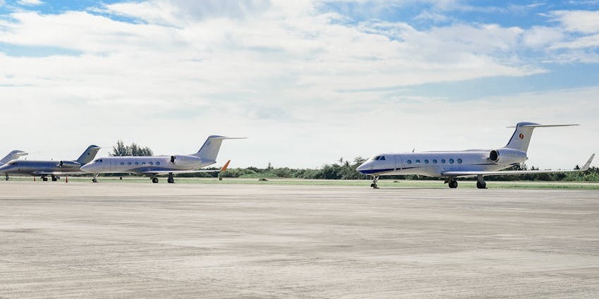 Commercial jet aeroplanes parked on the concrete runway of an airport under a cloudy sky