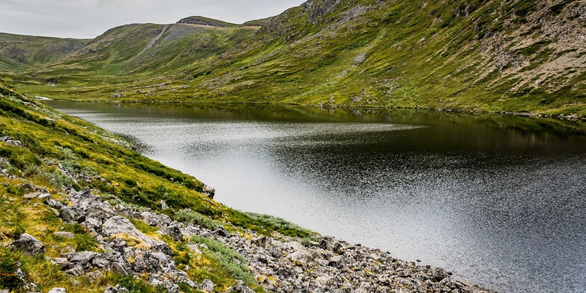 Shimmering water body surrounded by small green hills, one of the lakes in Oshawa, Canada.