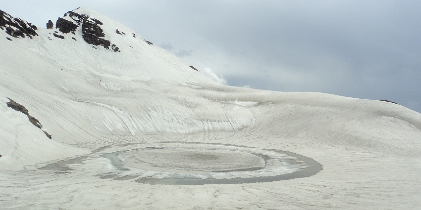 Brighu lake with a frozen water body, surrounded by white snow-covered land and mountains