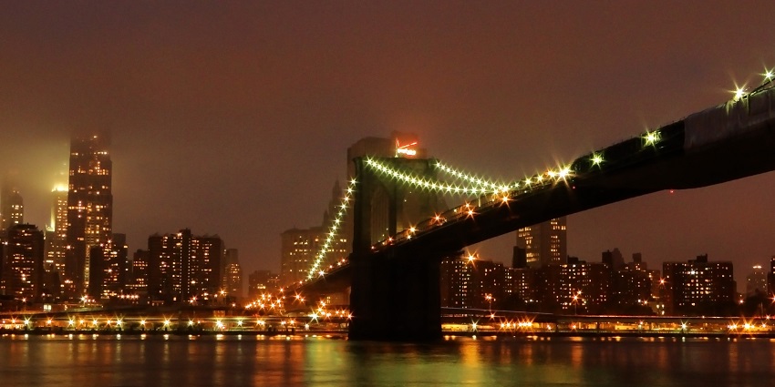 An image of Brooklyn Bridge at night, the best place to see lit up against the skyline.