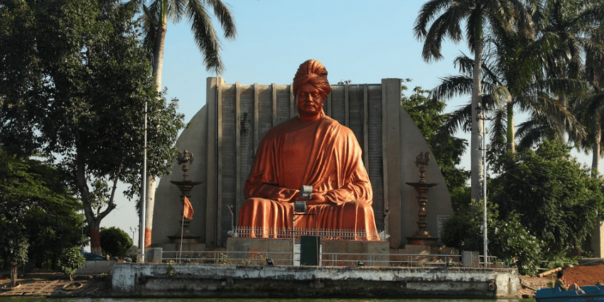 The statue of Swami Vivekanand well-illuminated at night behind the Budha Talab lake
