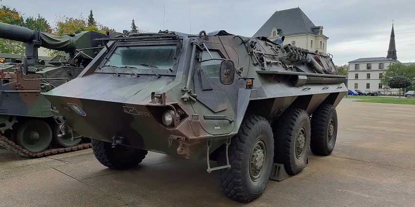 An image of a camouflage APC with six wheels in an open area in the Bundeswehr Museum of Military History.