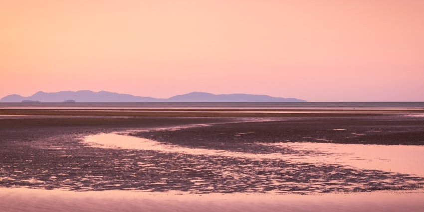 An image showing a pink sunset at Bushland Beach, one of the best beaches in Townsville.