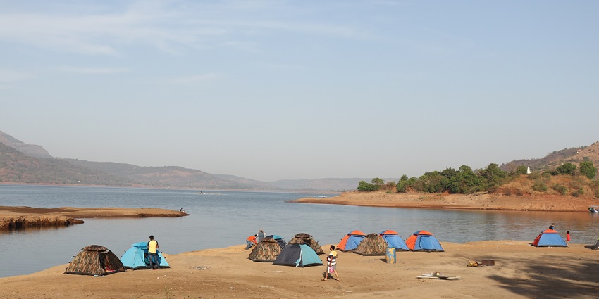 A picture of a campsite near the serene Pawna Lake early in the morning