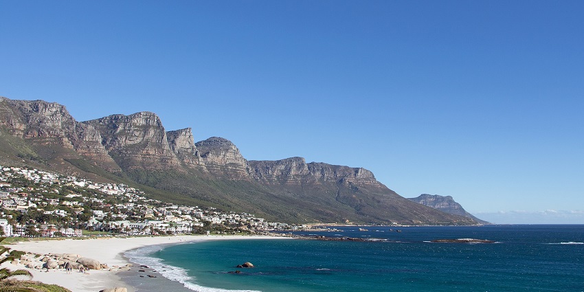 Camps Bay Beach with golden sands, blue waters, and the Twelve Apostles in the background.