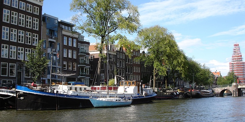 A canal cruise boat in Amsterdam, gliding through the water with scenic city views.