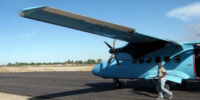 An aircraft on the runway of Cap-Haïtien International Airport with a man walking in front