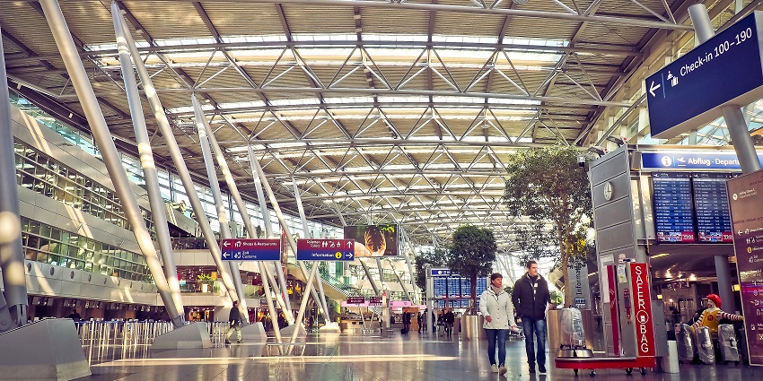 Passengers standing in the airport terminal while checking the flight information board.