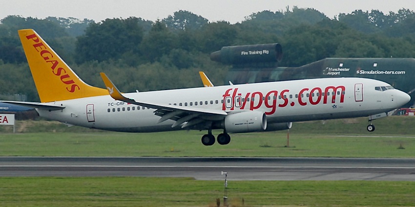 Commercial aeroplane taking off from the runway at the airport with surrounding green land