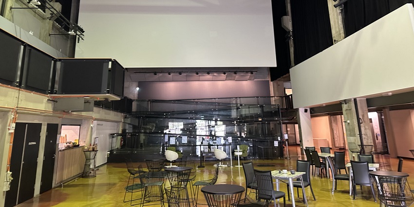 Inside the casula powerhouse arts centre with empty chairs and tables and a white screen