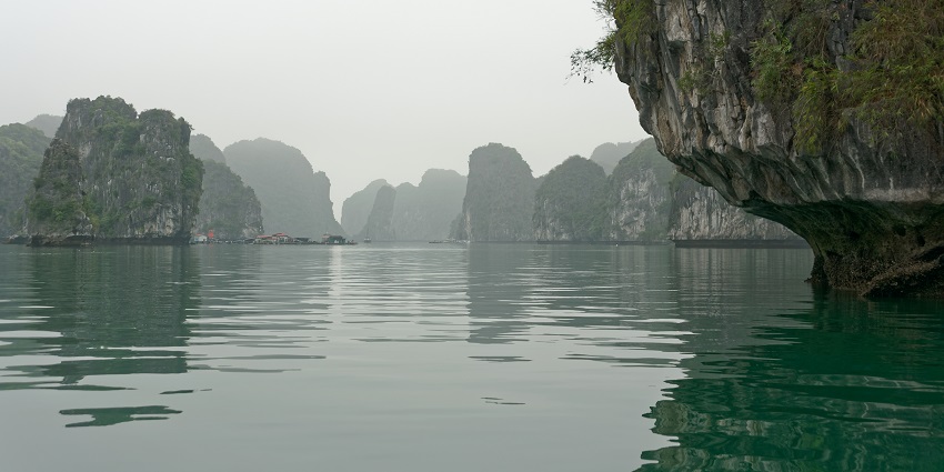 An image showing islands southeast of Cat Ba Island in Vietnam, with rocky cliffs and greenery.