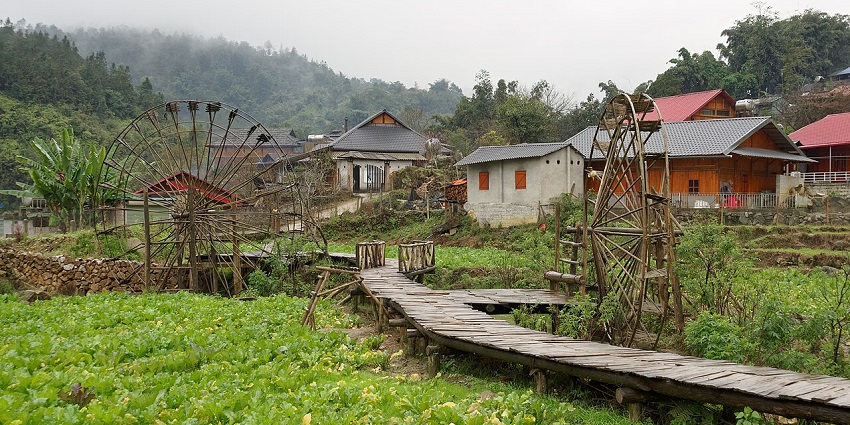 A photograph of Cat Cat Village, featuring traditional wooden houses and green valleys