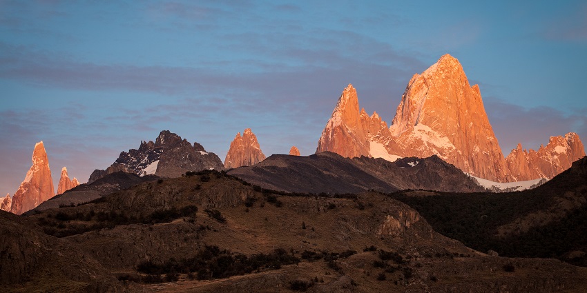 A breathtaking sunrise over towering peaks, casting a golden glow on rugged cliffs