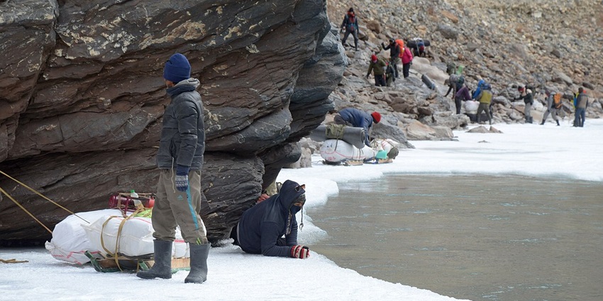 A frozen river with trekkers walking on the ice in Ladakh.