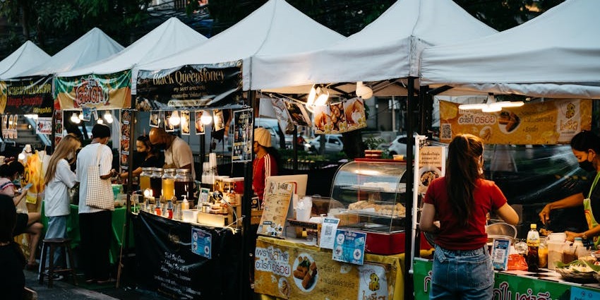 A vibrant market with street food stalls, fashion items, and handmade crafts.