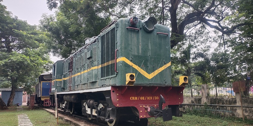A colourful image of the Chennai Rail Museum featuring locomotives, train bogies, and industrial rail equipment