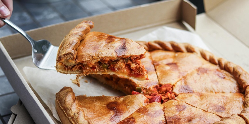 An image of a big, cheesy slice of Chicago deep-dish pizza topped with tomato sauce.