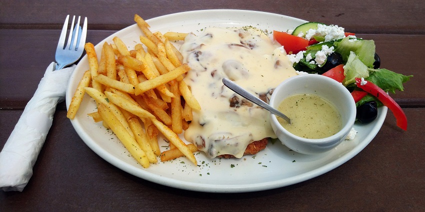 Chicken schnitzel with crispy potato fries, cheesy chicken and salad served with a sauce