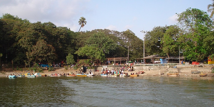 Lake with multiple small boats parked at the shore, people visiting and exploring