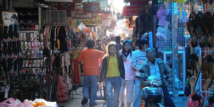 Commuters, shoppers, and Chinese merchants bustling through Chinatown Market in Bangkok.