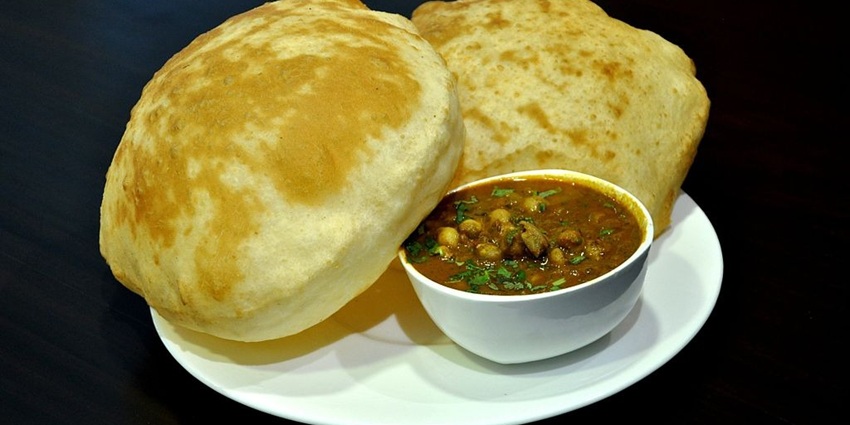 Plate of fluffy bhature with spicy chole, a North Indian classic served with onions and pickles