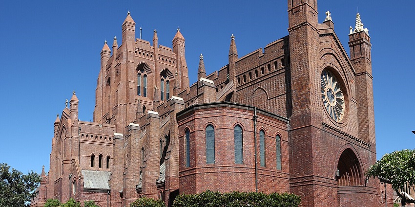 Christ Church Cathedral, one of the churches in Australia, with a large tower and Gothic elements in warm daylight.