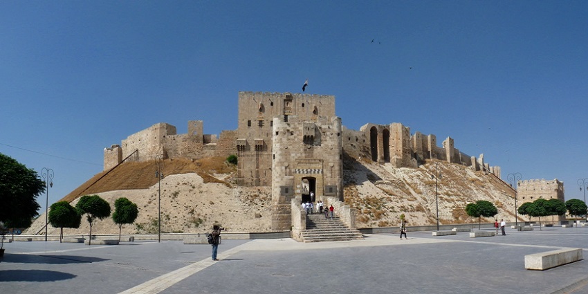 A few tourists exploring and climbing to the main entrance of Citadel of Aleppo, Syria.