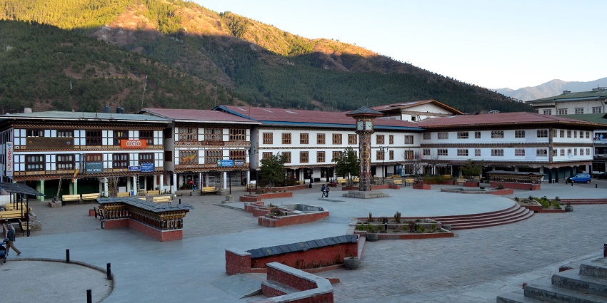 A lively public square in the chorten, featuring a traditional Bhutanese-style clock tower surrounded by shops and restaurants.