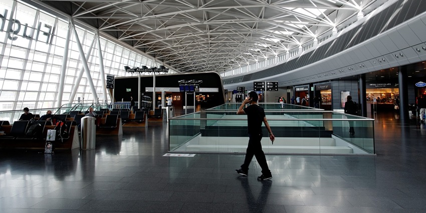 A departure hall of an airport with a man walking while holding a phone to his ear