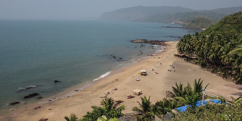 An aerial view of Cola Beach featuring shimmering waters and golden pristine sands.