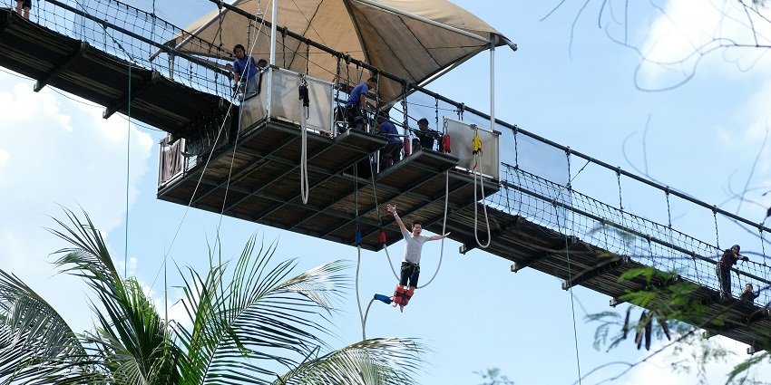 A man mid-fall during bunjee jumping in South Goa, descending with arms outstretched at Colva Adventure Park.