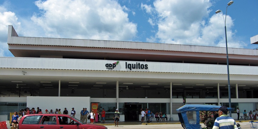 Coronel FAP Francisco Secada Vignetta International Airport, Iquitos with 'Iquitos' sign on the terminal, crowded with travellers, a red car, and a taxi