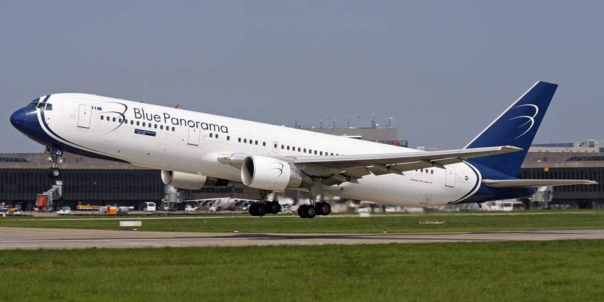 Dark blue and white commercial aeroplane taking off at Corozal Airport with runway