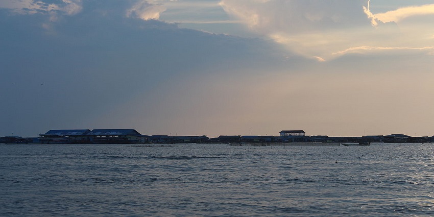 Tonle Sap Lake, reflecting gentle waves, bordered by buildings, peacefully nearby shores