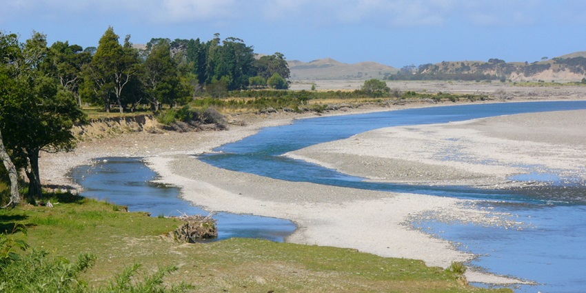 Image of the Hawke’s Bay trails, surrounded by greenery and trees, under a partly cloudy sky.