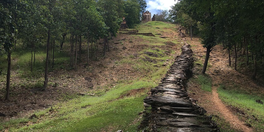 A serene forest path with scattered stones to Wat Saphan Hin's hilltop site, perfect for cycling.
